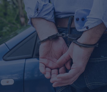 A person with their hands handcuffed behind their back.